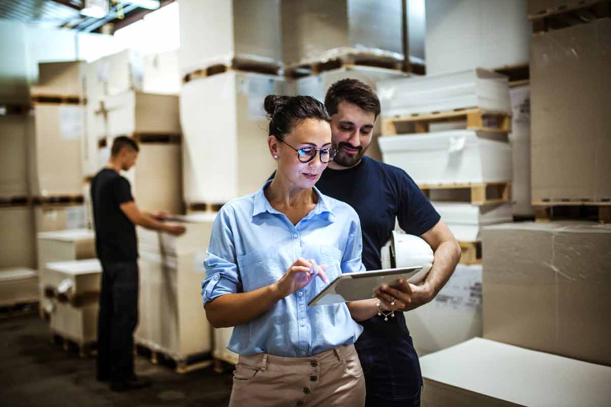 Un homme et une femme qui consulte une tablette dans un entrepÃ´t.